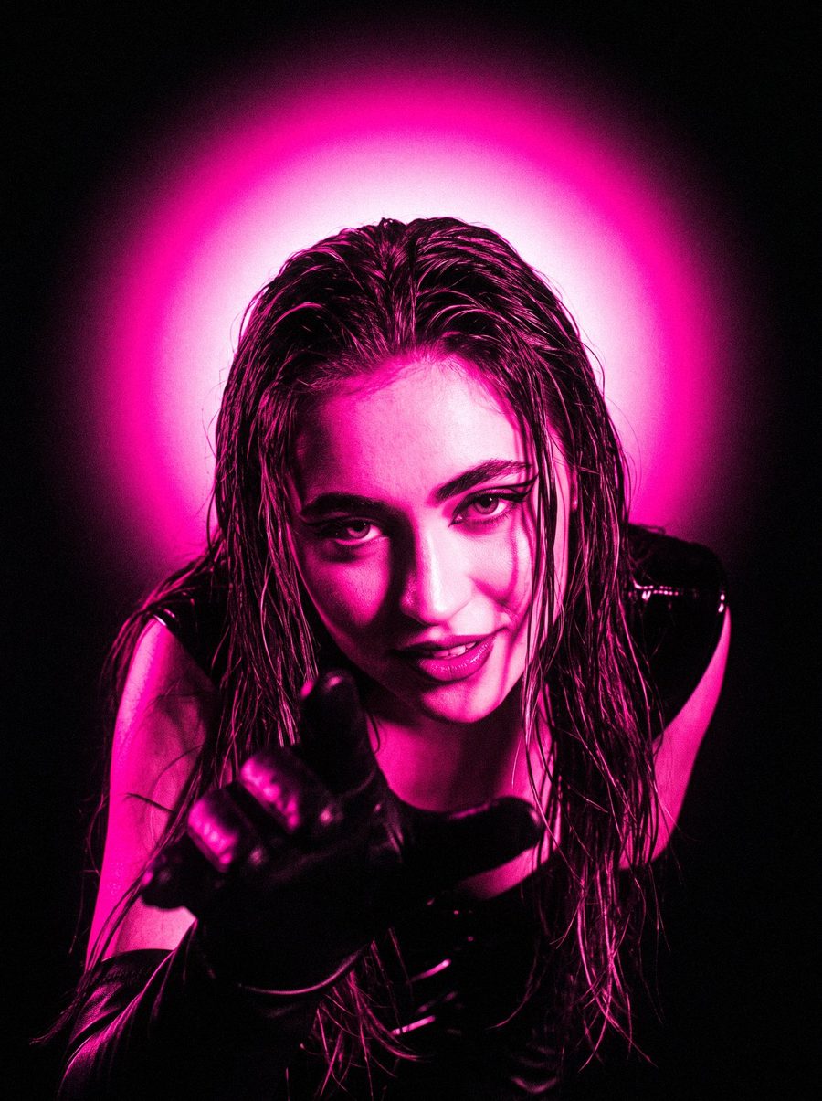 Victoria Grace leaning into the lens under a pink halo of light