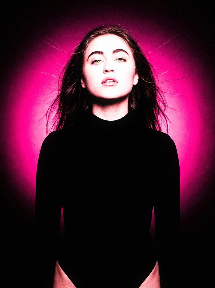 Victoria Grace with her hair blown back against a pink glow